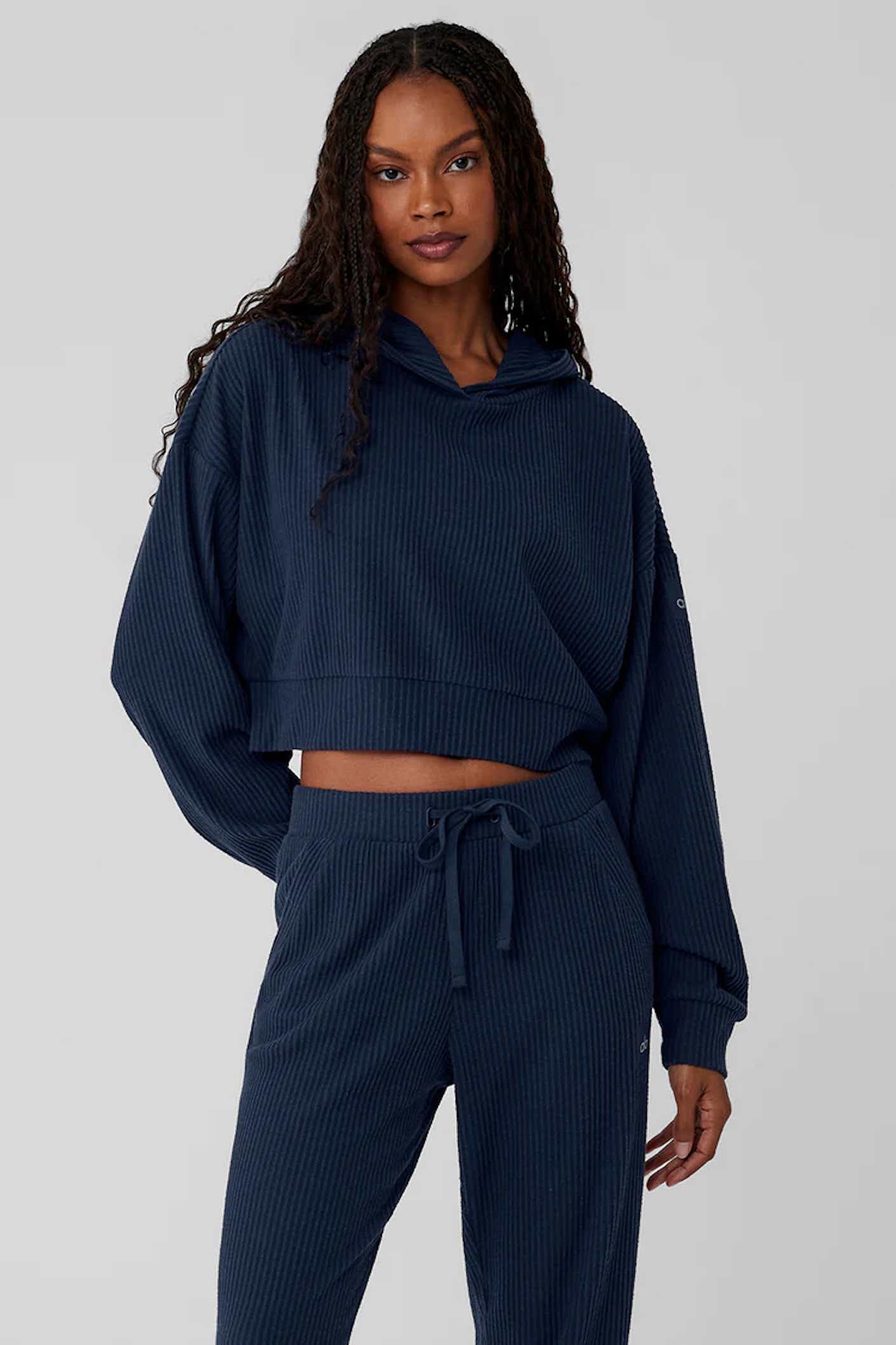 A model wears a navy blue hoodie and sweats.