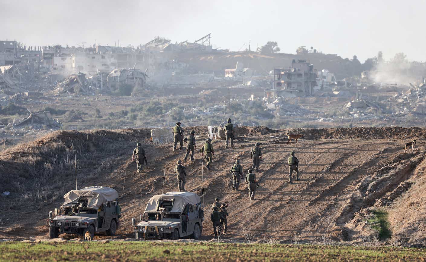 A picture taken in southern Israel near the border with the Gaza Strip on December 11, 2023, shows Israeli army soldiers taking position on a hill overlooking northern Gaza, amid continuing battles between Israel and the militant group Hamas. (Photo by Menahem KAHANA / AFP)