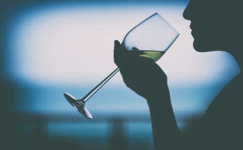 Silhouette image of a woman holding a wine glass to drink with blurred sea background