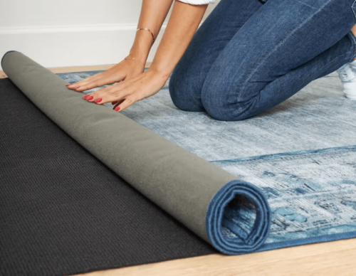 Person rolling Ruggable topper onto rug pad. 