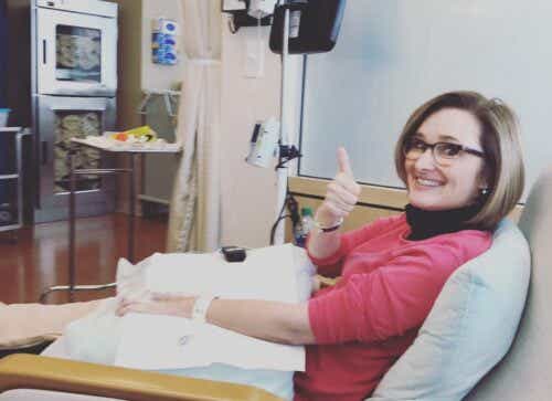 Kim McClellan gives thumbs up in hospital bed.