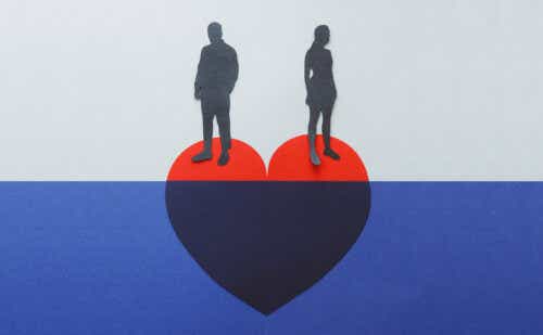 A couple stands on either side of a red heart suspended in blue water.