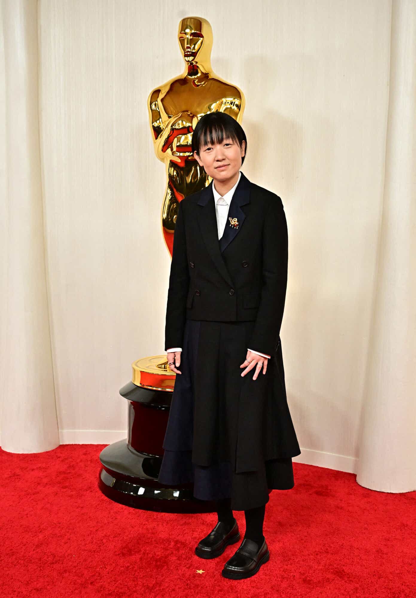 Celine Song wears a blazer and a pleated skirt to the Oscars.