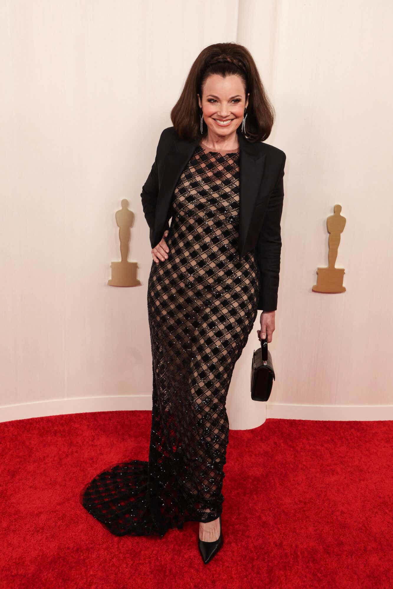 Fran Drescher arrives at the Oscars wearing a sheer gown with black sequined checker overlay and a cropped black blazer.