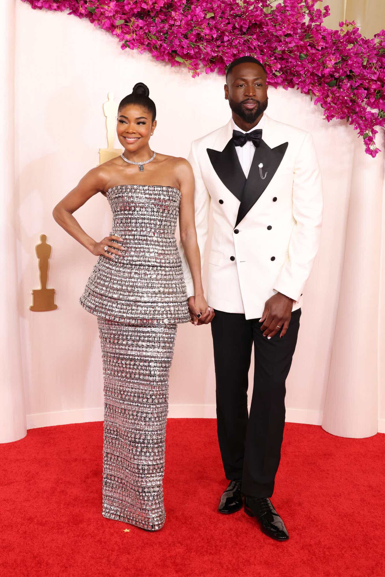 Gabrielle Union wears a bejeweled silver gown that's stapless with a peplum skirt. Dwyane Wade wears a white tux jacket and black trousers with a black bowtie.