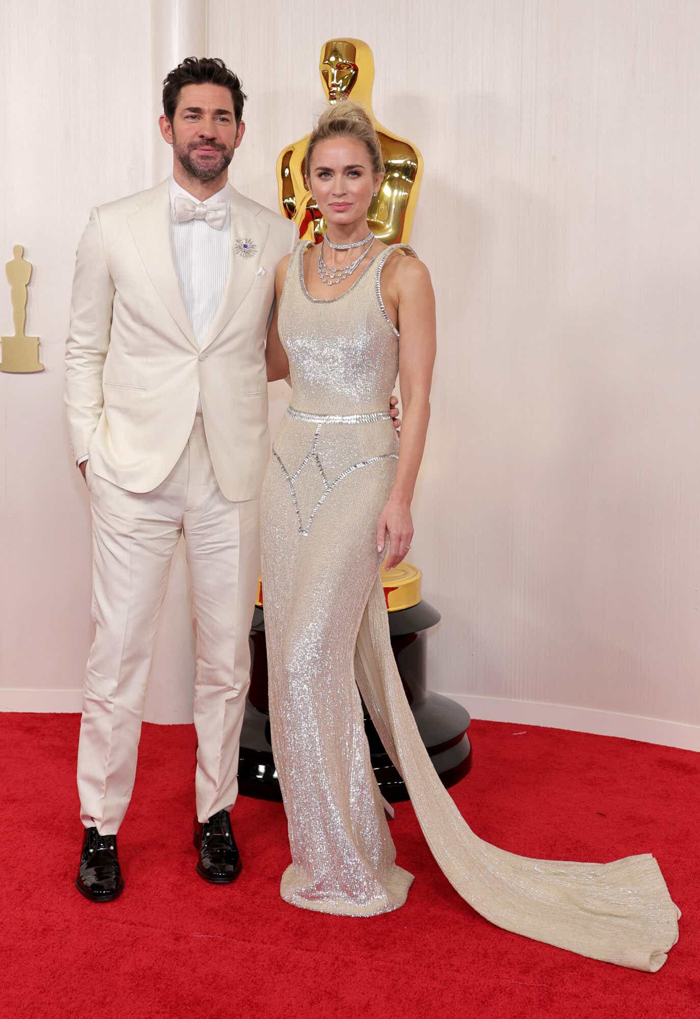 John Krasinski (left) in a white tux and a bow tie. Emily Blunt (right) wears a white sequin gown with floating straps.