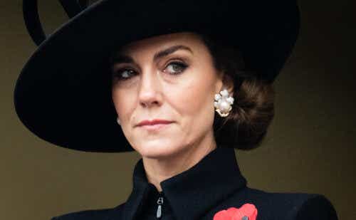 Kate Middleton wearing a black fascinator and a high-neecked black goat with her hair in a lot knot.
