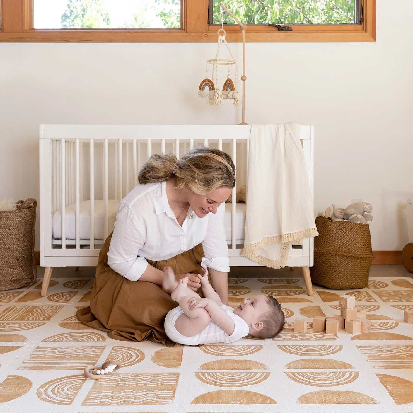 A mother and baby on a floor mat
