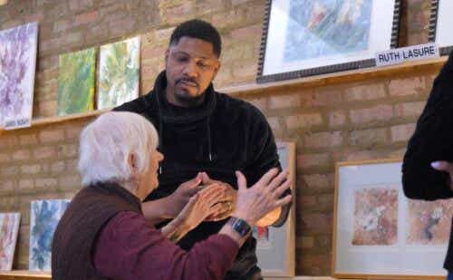 an older woman talking to a man in an art gallery
