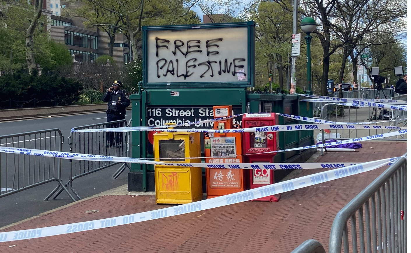 Police tape blocks off pavement near a subway entrance at Columbia that's been spray-painted with "Free Palestine"