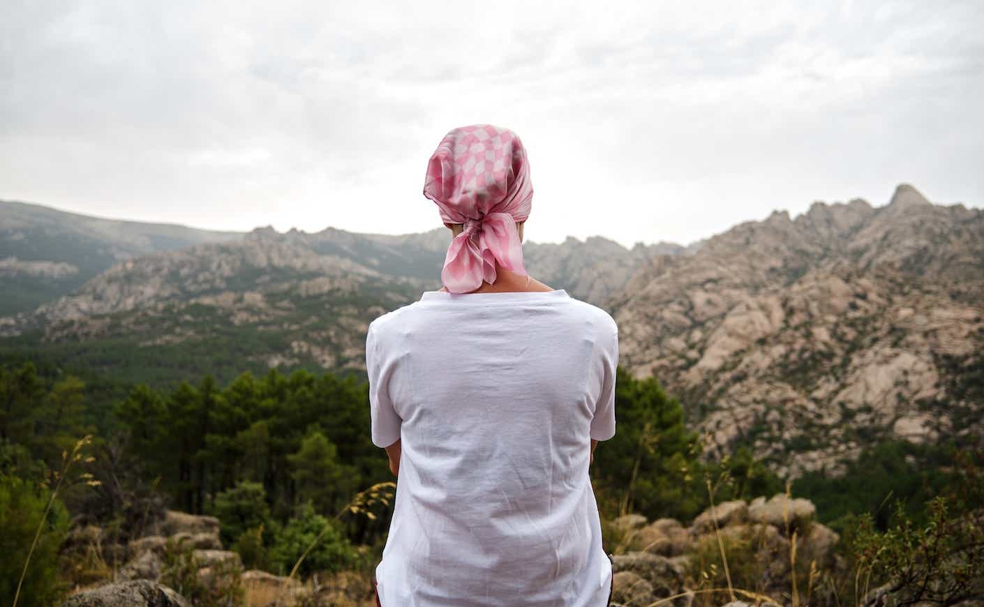 woman with a pink bandana on her head looking out at a vista