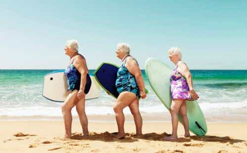 three older women carrying boogie boards on the beach