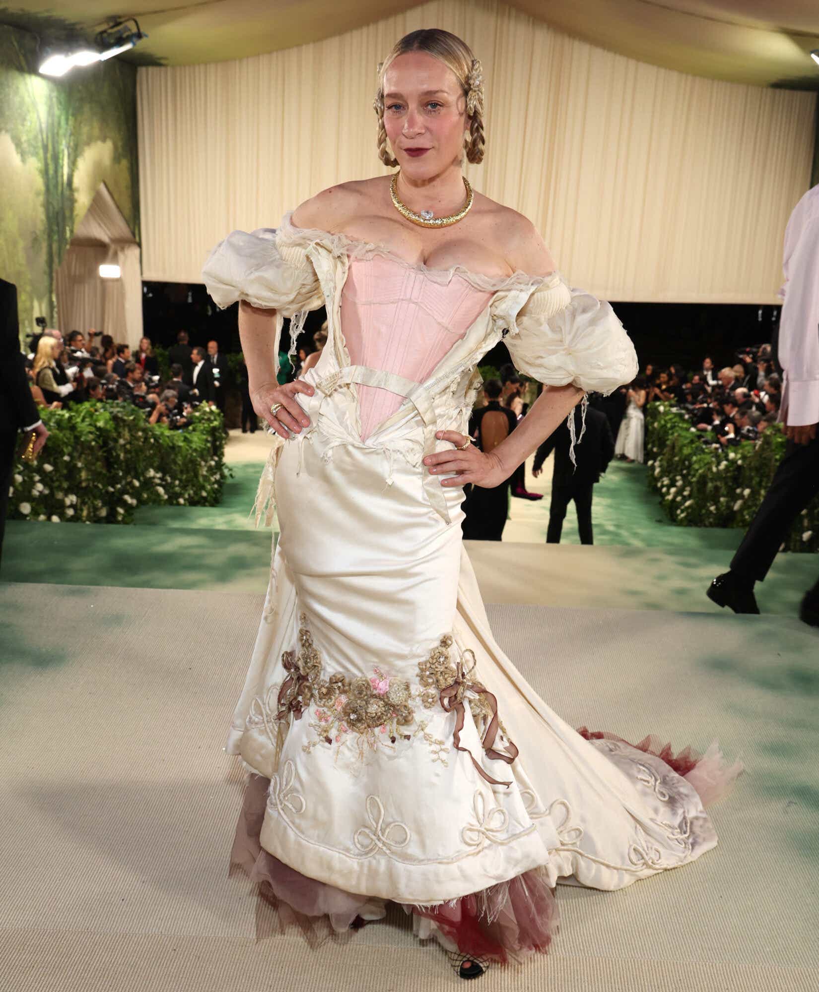 Chloë Sevigny wears a distressed Cinderalla-style cream dress torn at the front to reveal a pale pink bodice.