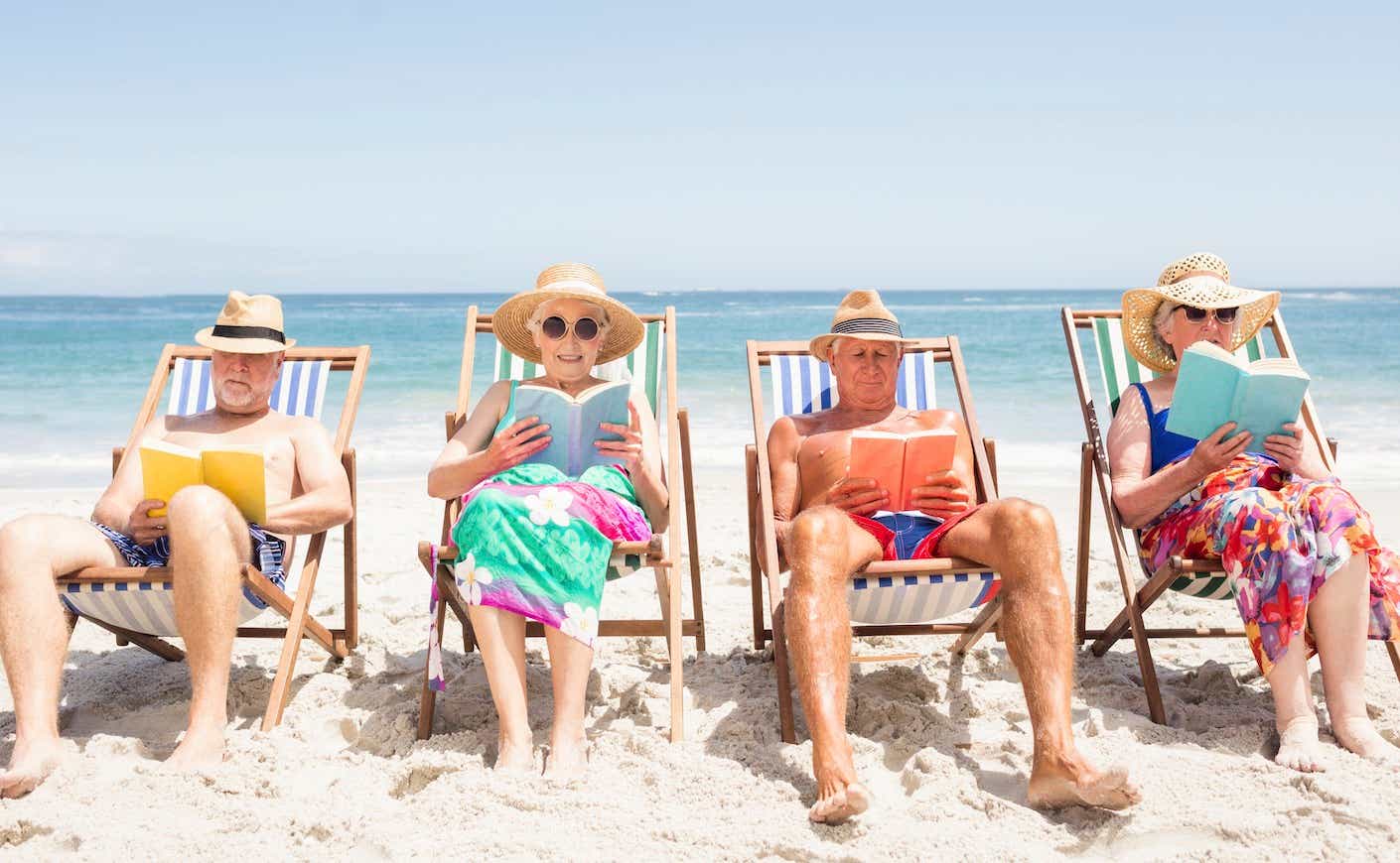 a group of older people reading books on the beach