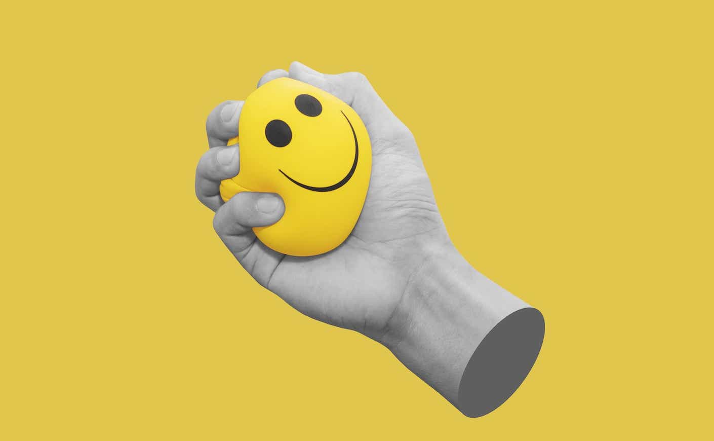 hand squeezing a stress ball that has as smiley face on it