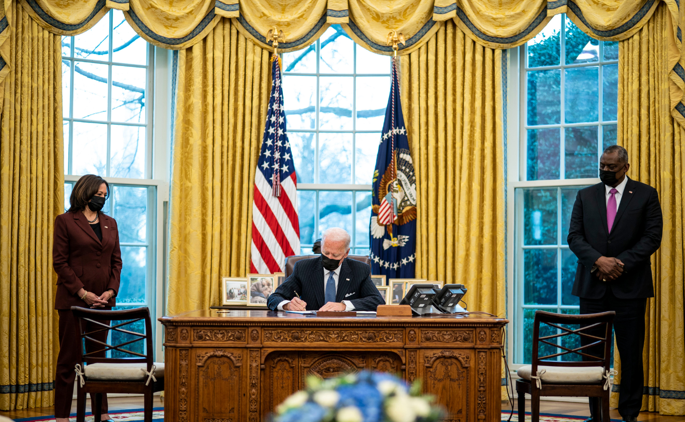 Flanked by Vice President Kamala Harris and Secretary of Defense Lloyd Austin, President Joe Biden signs an executive order repealing the ban on transgender people serving openly in the military on Jan. 25, 2021.