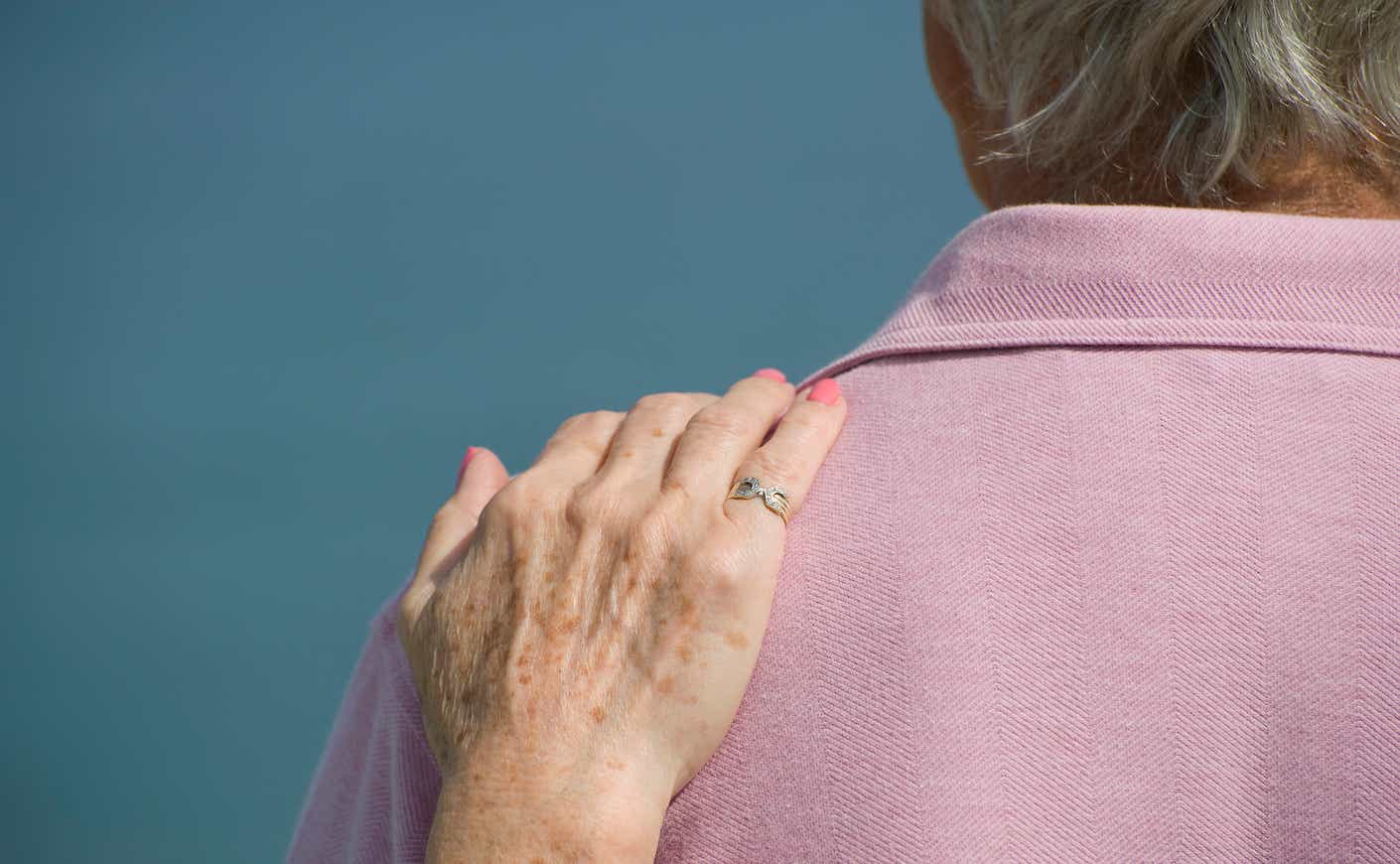 Elderly lady resting her hand on her partners shoulder