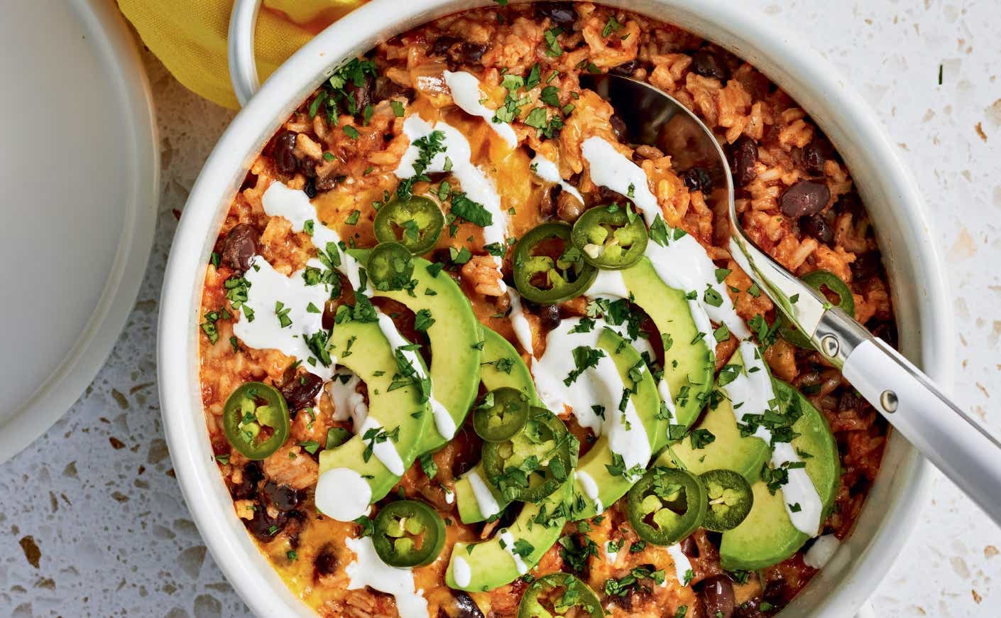 A bowl of rice, beans, avocado, and sour cream.