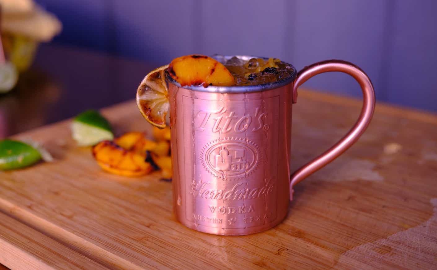 A copper cup with a grilled peach garnish