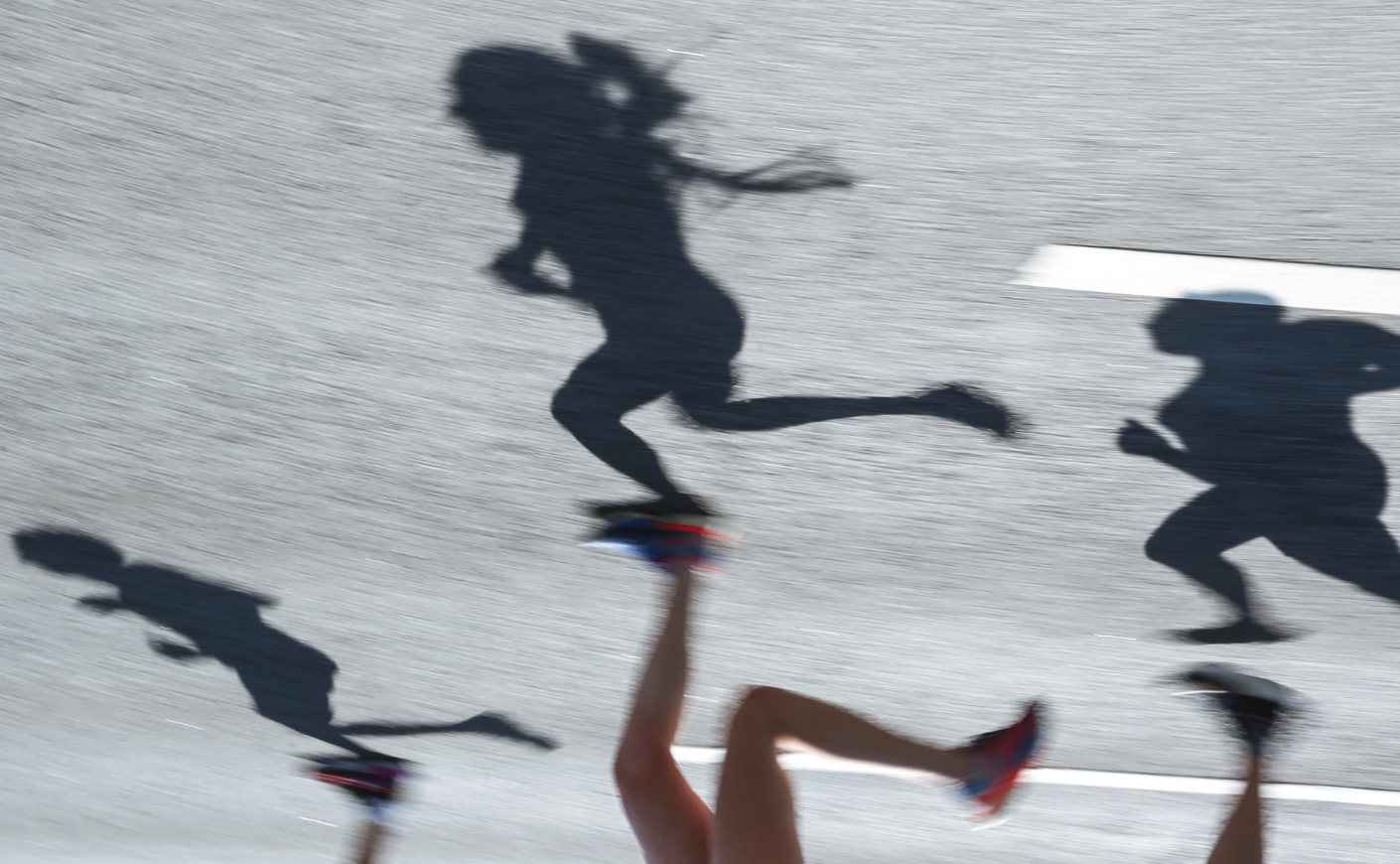 Shadows of women running on the pavement