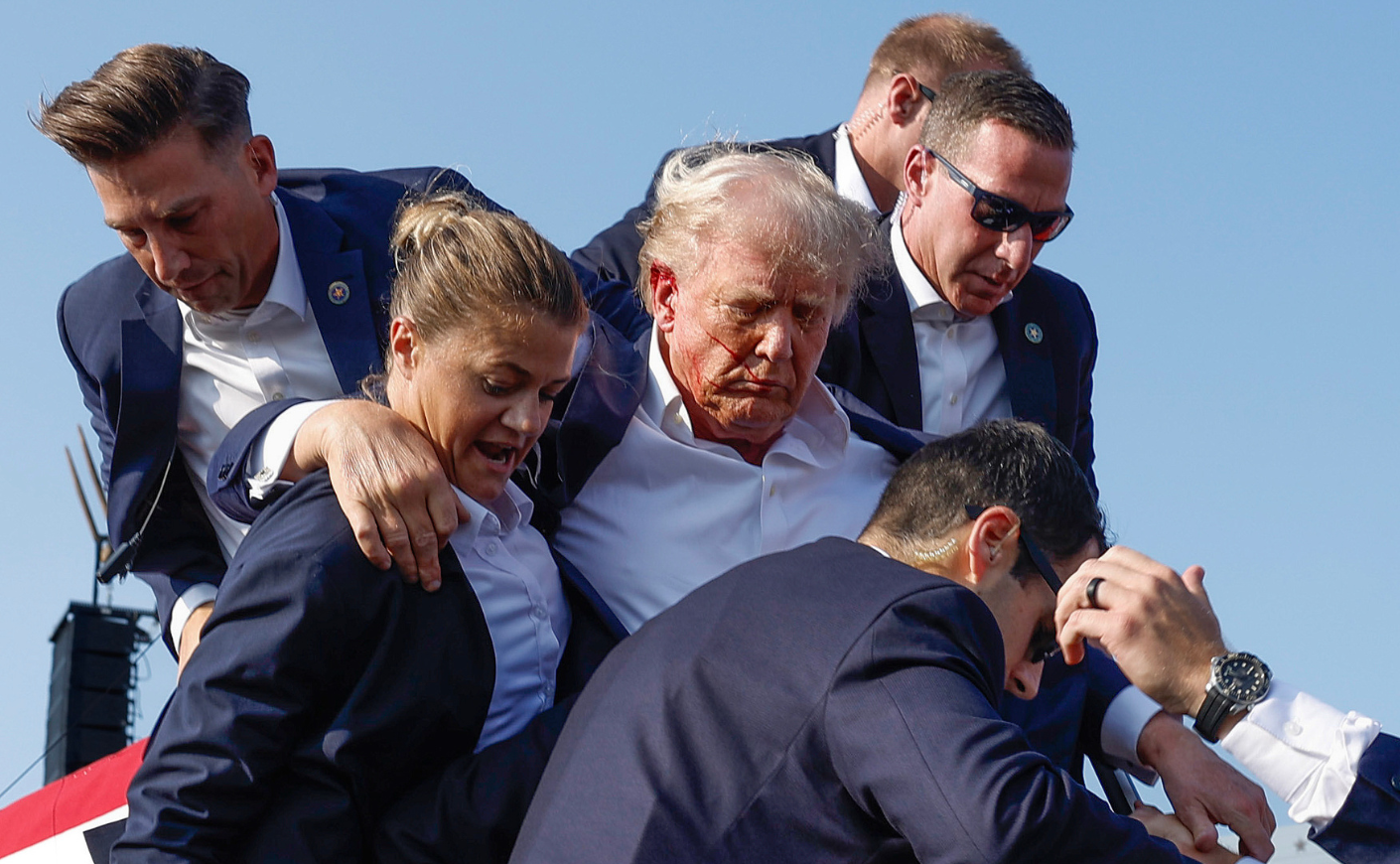 Secret Service agents escort Donald Trump offstage after he was shot