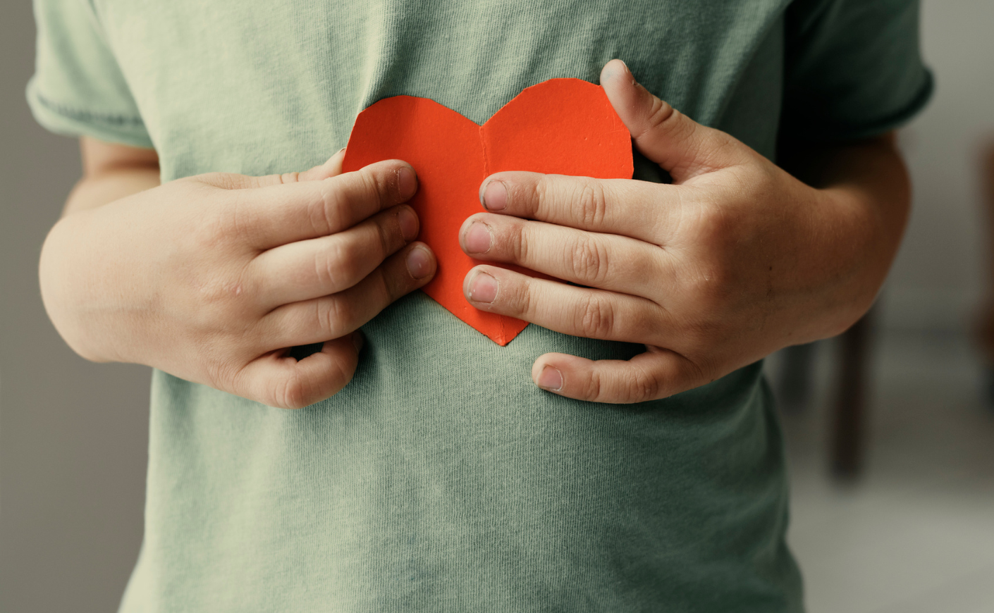 child holding a heart up to its chest