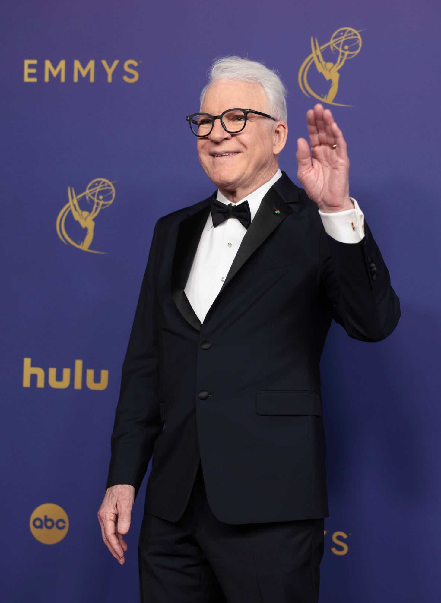 Steve Martin waves in a black tux with a white shirt.