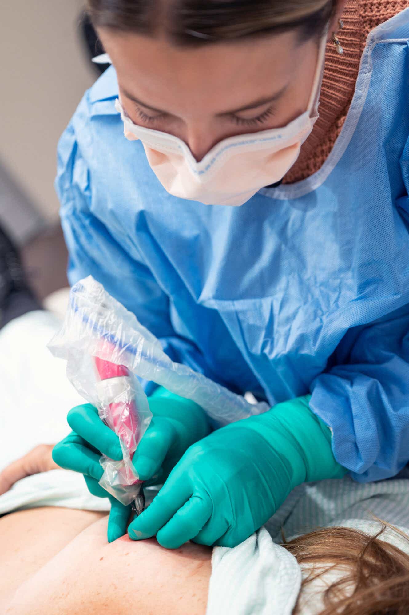 Close up of tattoo artist working on a patient