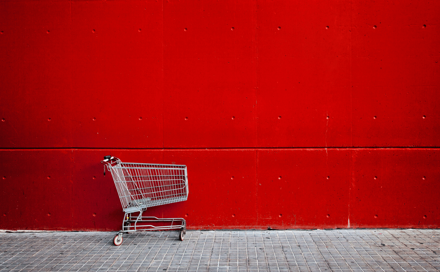 empty shopping cart on a red wall