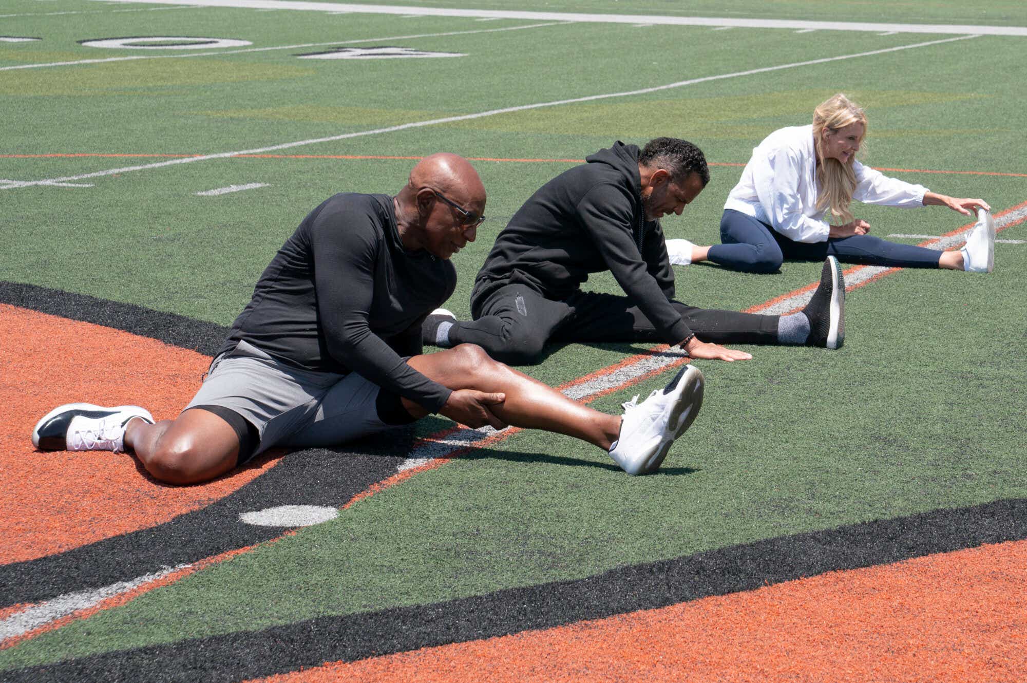 Andre Reed, Eric Dickerson and Joan Vassos stretch their hamstrings