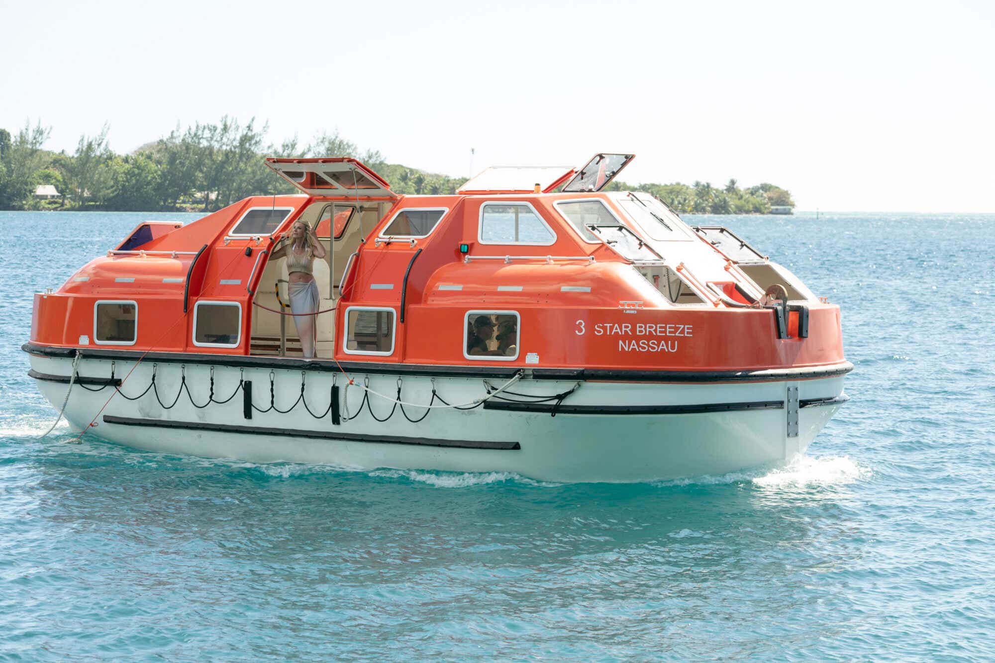 Joan Vassos standing on a red and orange schooner