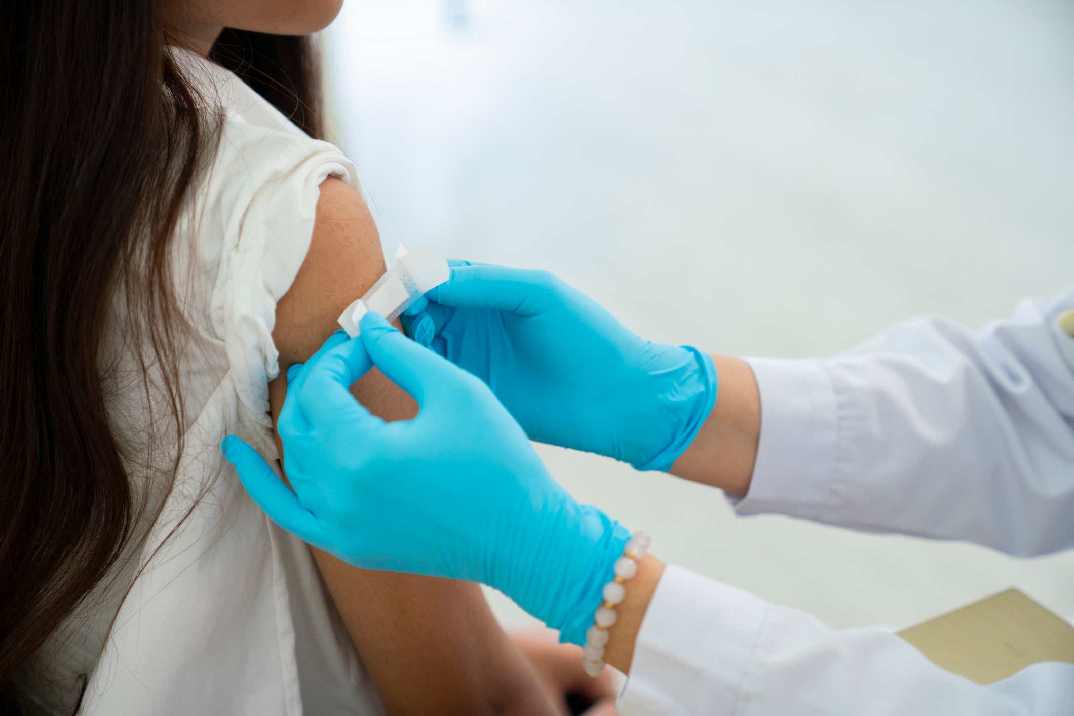 Doctor putting a bandage on a patient's arm after a flu vaccine