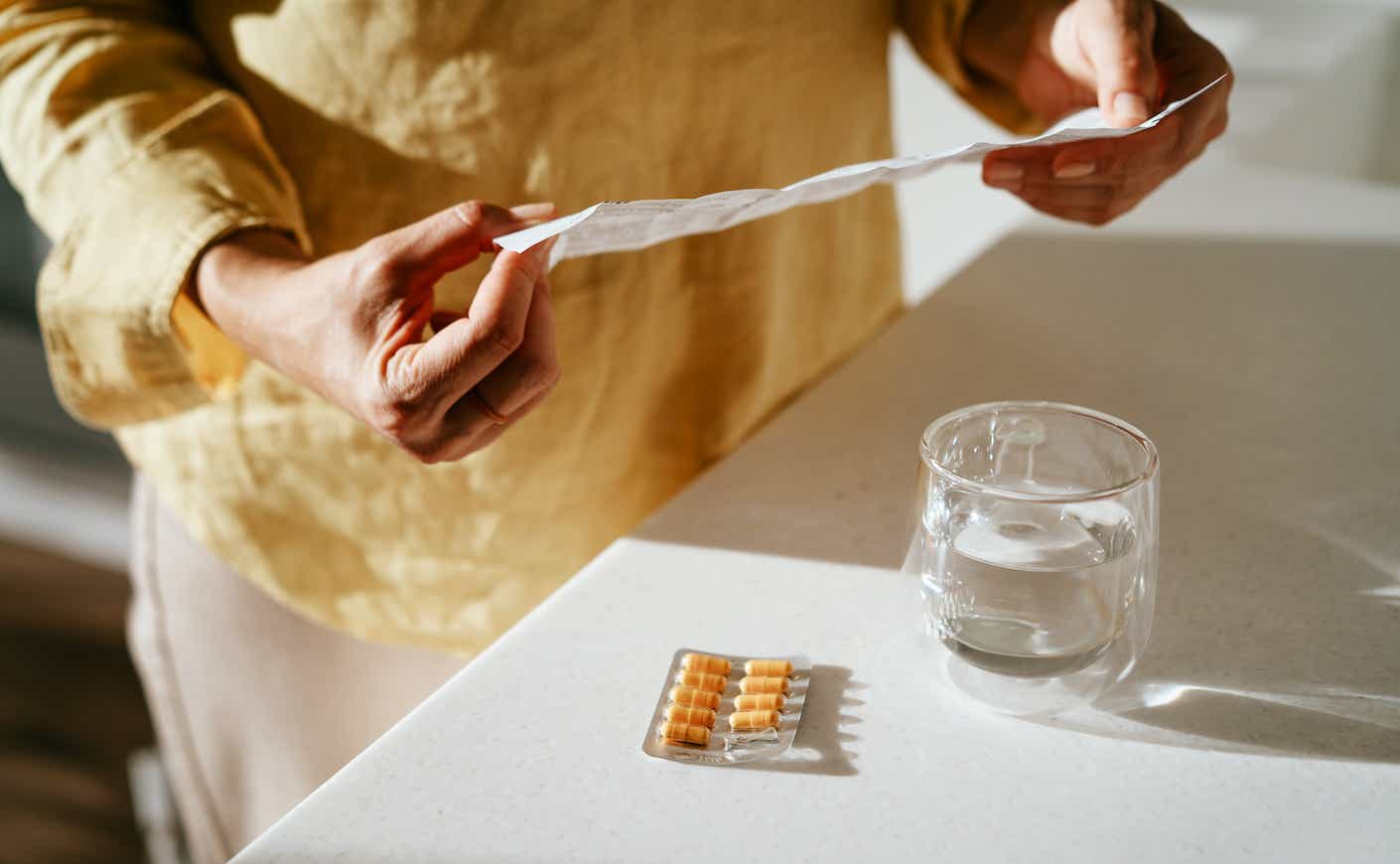 A woman standing at a table with green pills in her hand