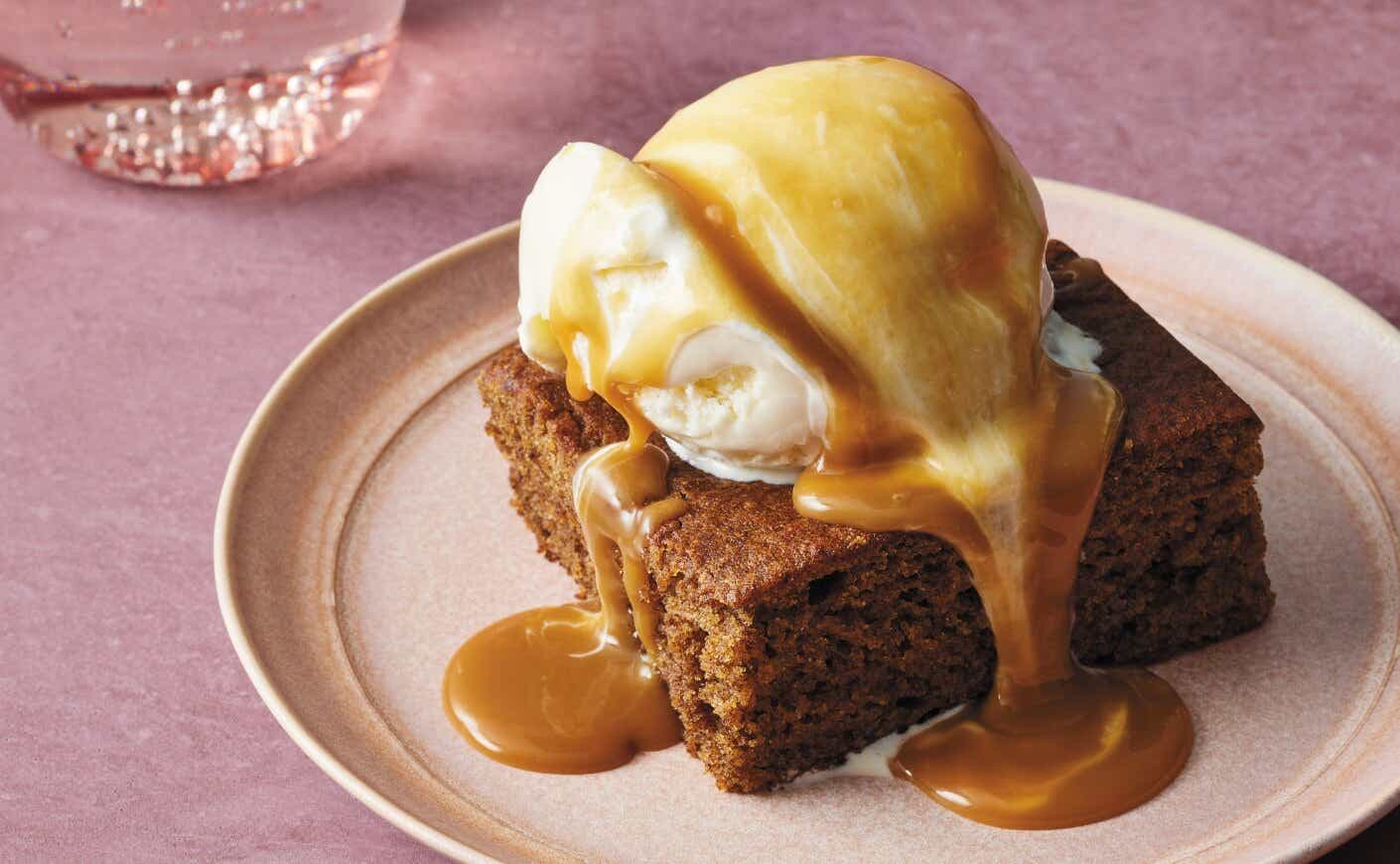 a piece of sticky date cake with ice cream and caramel sauce.