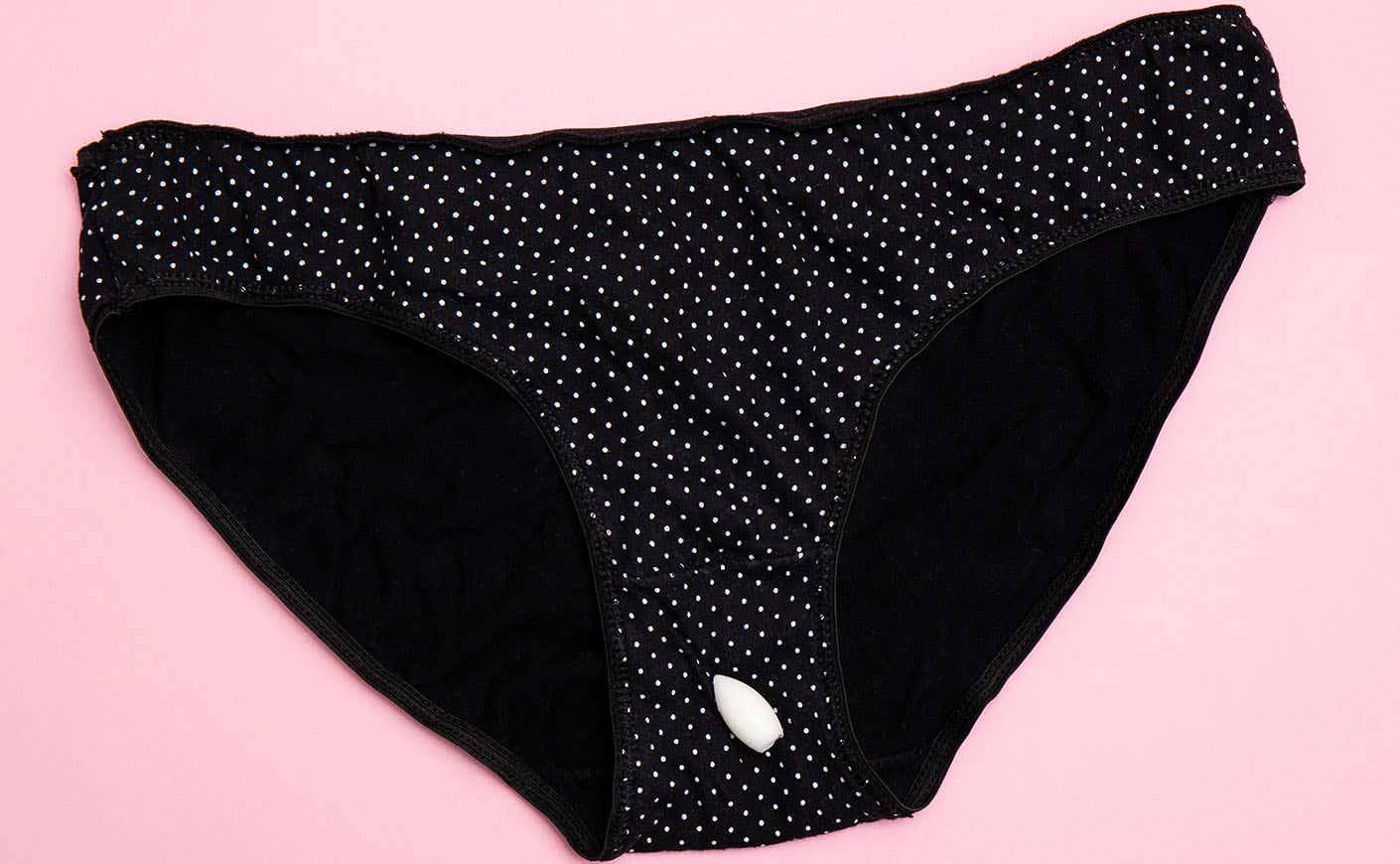 A pair of black underwear briefs with white polka dots and a vaginal suppository on top of them