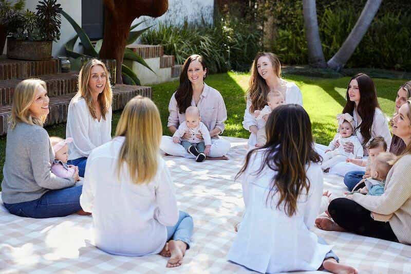 group of moms and babies sitting in a circle outside