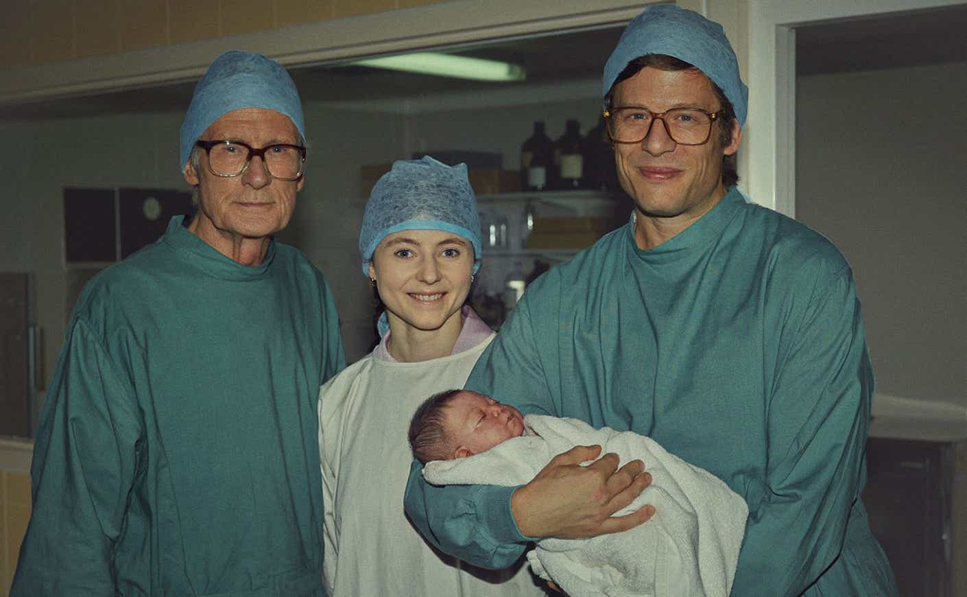 bill nighy, thomasin mckenzie, james norton holding a baby wearing scrubs on set of Joy