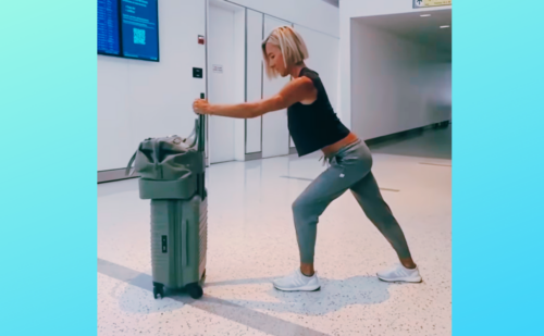 woman stretching while holding onto a suitcase