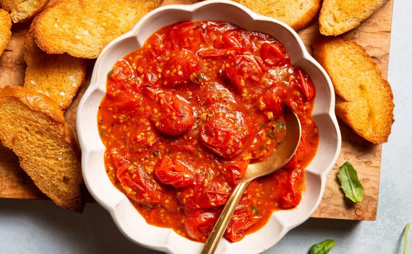 A dish of tomato dip surrounded by crackers.