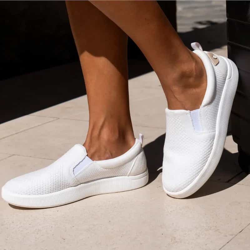 woman's legs in white slip on shoes