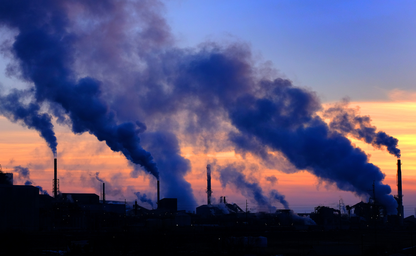 A factory emits pollution into the air at sunset