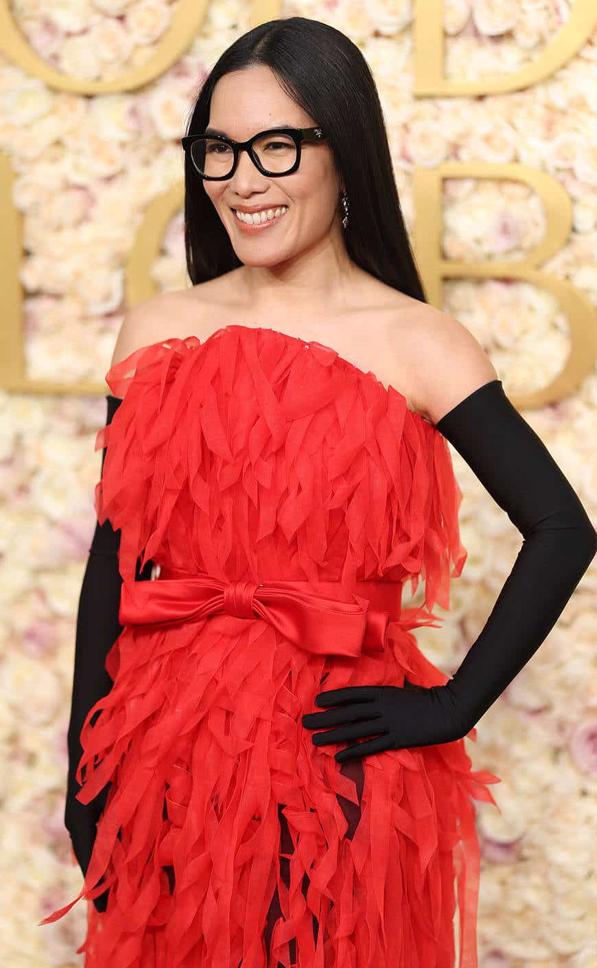 Ali Wong wears a fringed strapless red gown with black gloves to the Golden Globes.