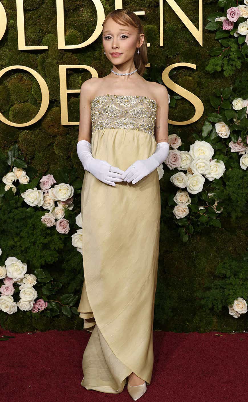 Ariana Grande wears a yellow strapless sheath gown with a banded sequined top and white gloves.