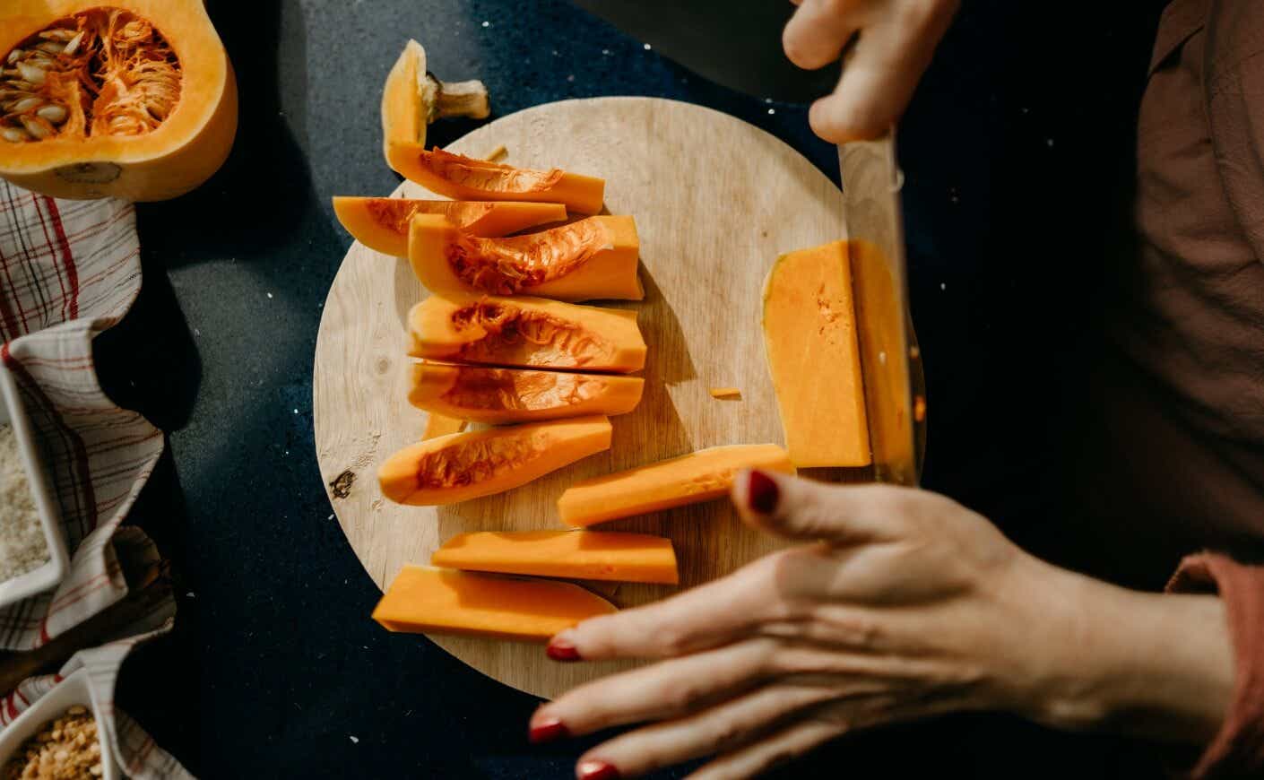 Two hands cutting squash on a cutting board.