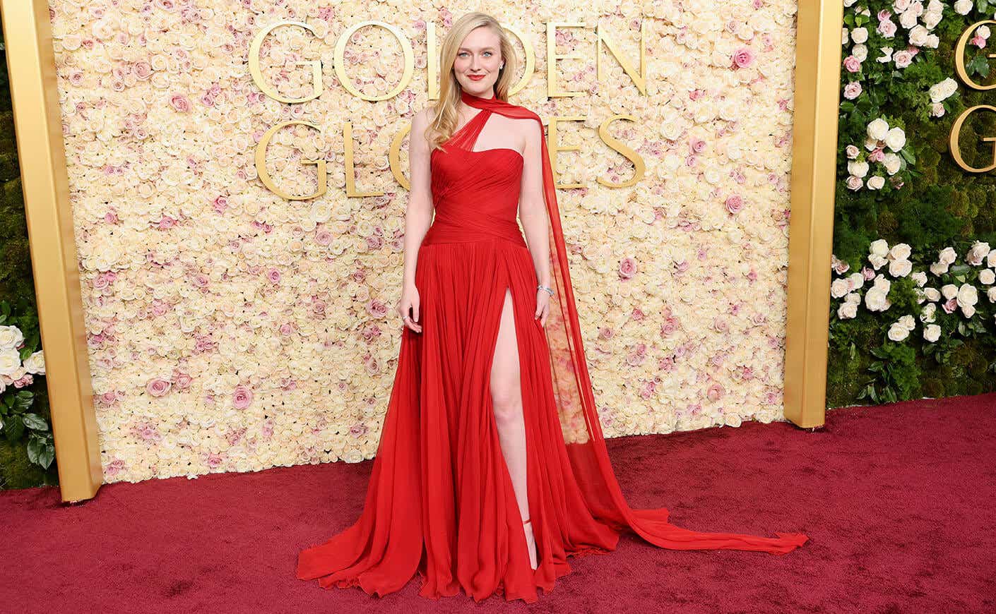 Dakota Fanning wears a drapey one-shoulder red gown with a halter neck and a thigh-high slit.