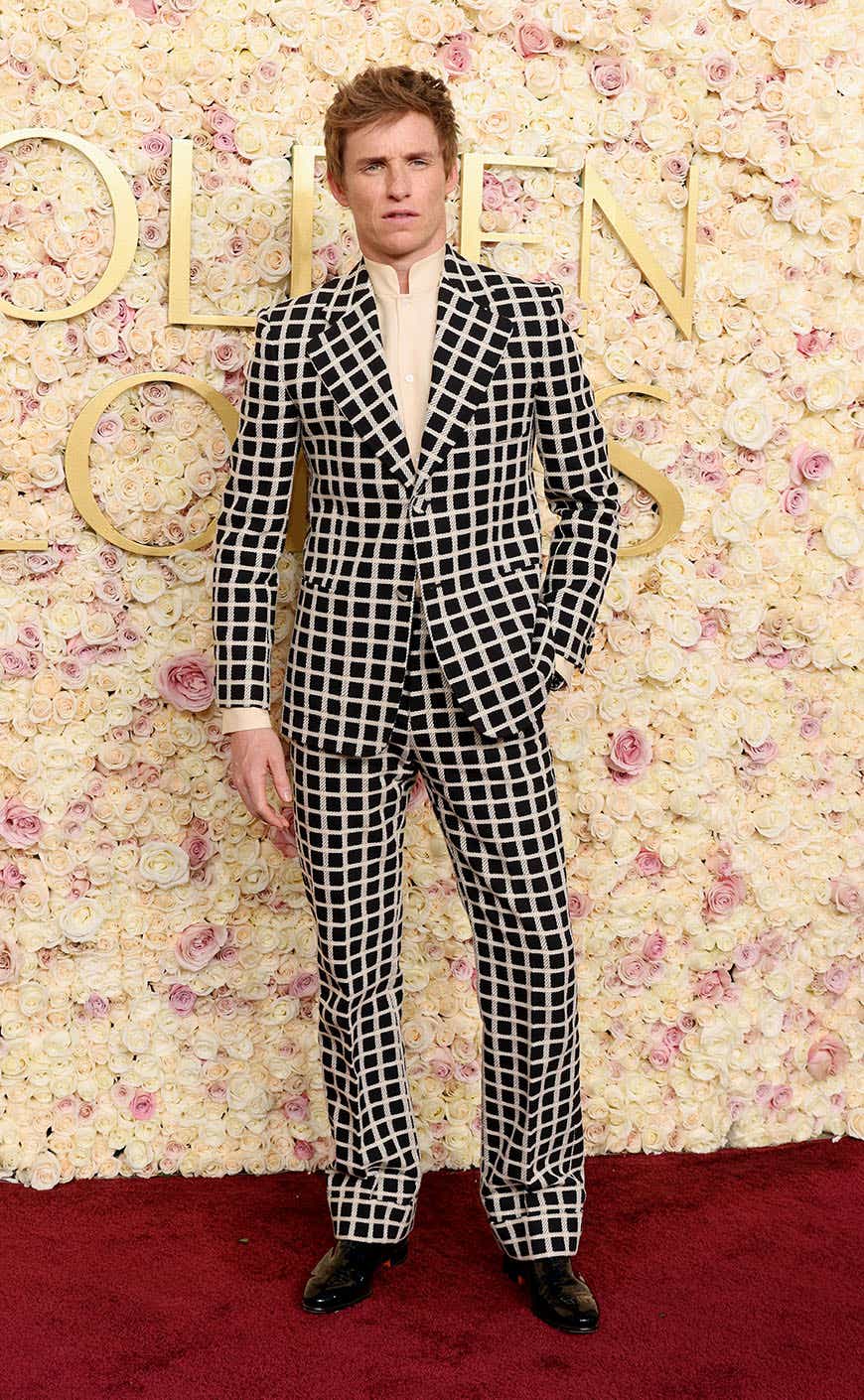 Eddie Redmayne wears a checkered black-and-cream suit to the Golden Globes.