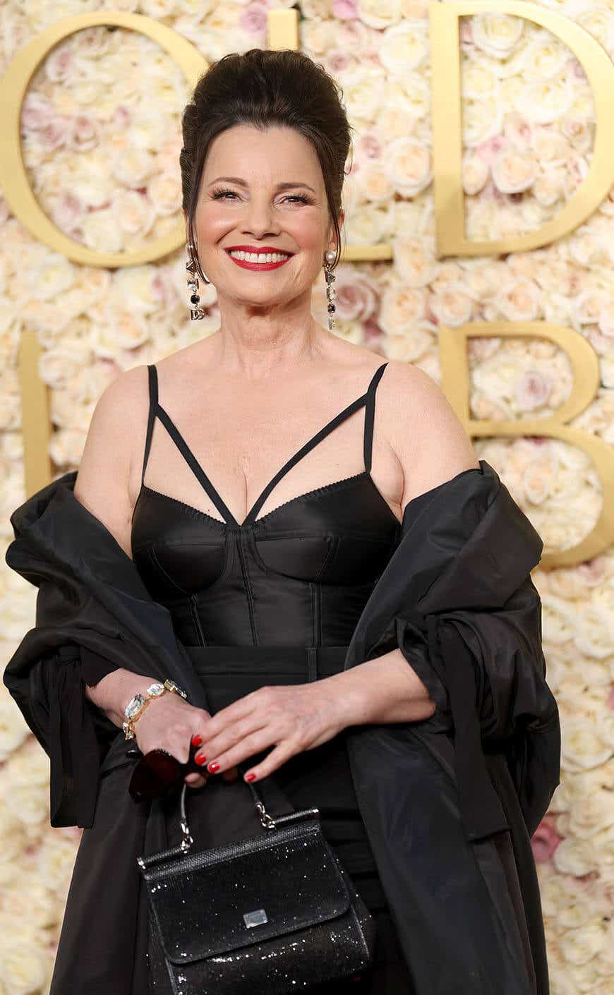 Fran Drescher wears a black gown with a corset top and matching shawl to the Golden Globes.