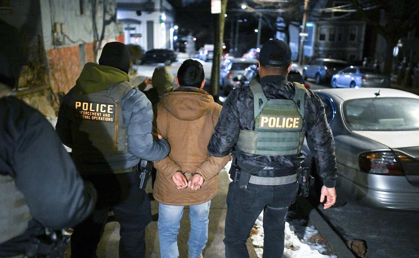 a man is escorted by police in handcuffs