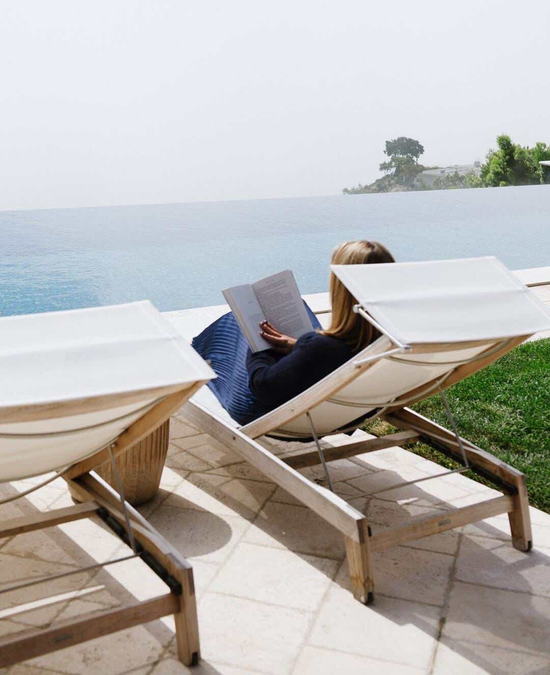 zibby owens sitting by a pool reading