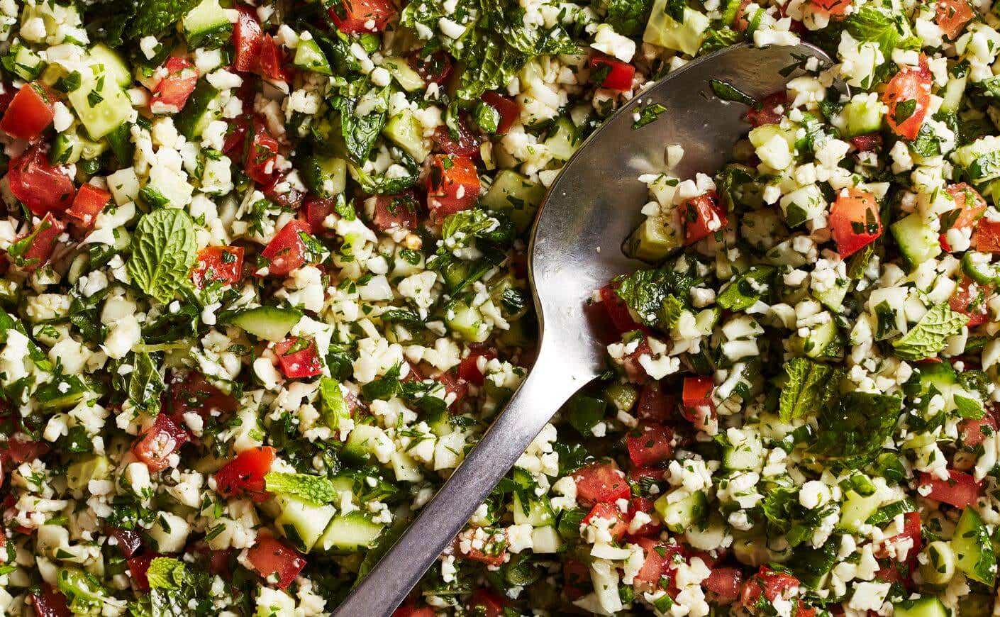 A spoon dipping into low carb cauliflower tabbouleh